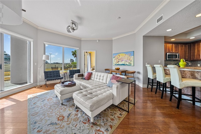 living room with ornamental molding, dark wood-type flooring, and a textured ceiling