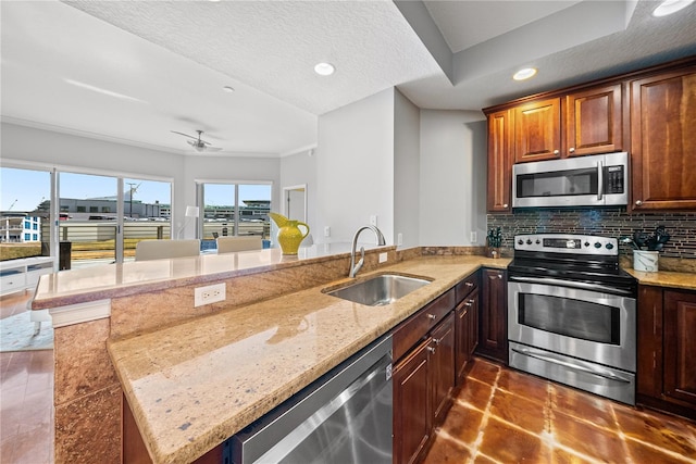 kitchen with tasteful backsplash, appliances with stainless steel finishes, a textured ceiling, sink, and kitchen peninsula