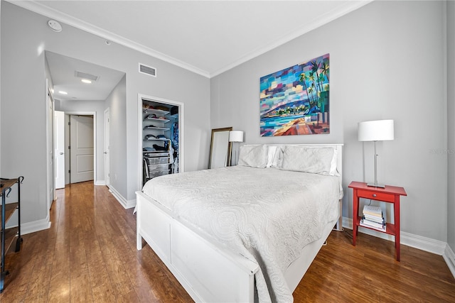 bedroom with dark wood-type flooring, crown molding, and a closet