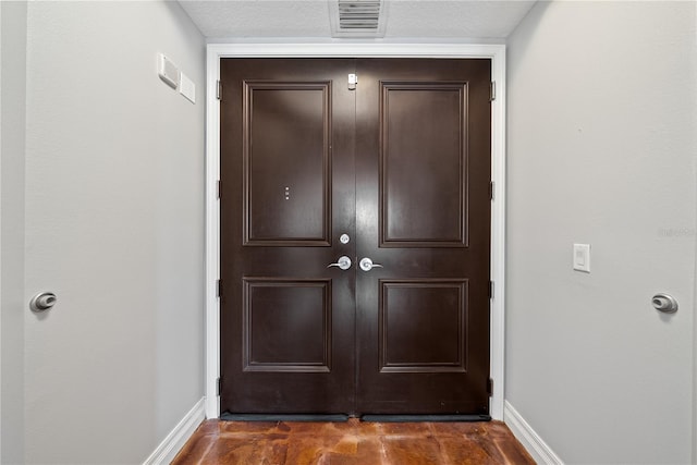 doorway to outside with a textured ceiling