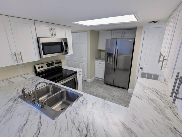 kitchen featuring white cabinetry, light stone counters, appliances with stainless steel finishes, and sink