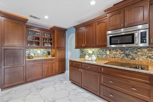 kitchen with black electric cooktop, decorative backsplash, and light stone countertops