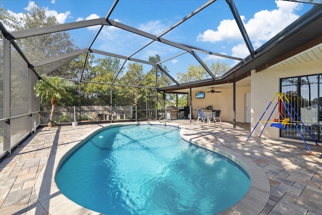 view of swimming pool with a patio area, glass enclosure, and ceiling fan