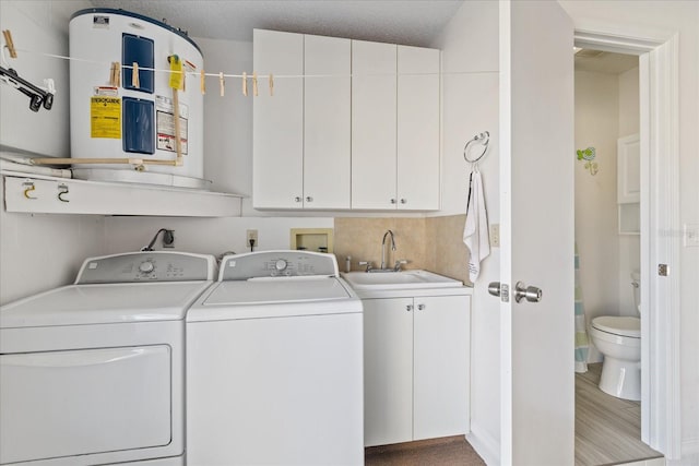 clothes washing area with a textured ceiling, sink, washing machine and clothes dryer, and cabinets