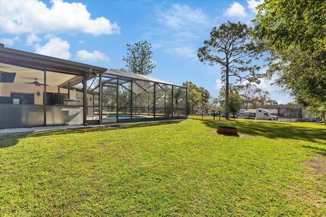 view of yard featuring a patio, ceiling fan, and glass enclosure