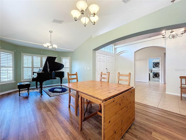 dining room featuring washer / dryer, wood-type flooring, vaulted ceiling, and a wealth of natural light