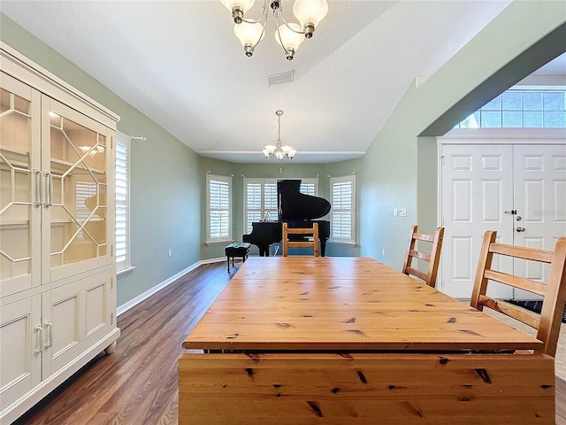 dining room with dark wood-type flooring, lofted ceiling, and an inviting chandelier