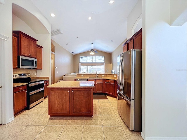 kitchen featuring lofted ceiling, a kitchen island, sink, light tile patterned floors, and appliances with stainless steel finishes