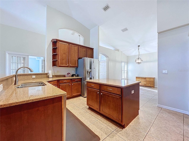 kitchen with sink, kitchen peninsula, decorative light fixtures, light tile patterned floors, and stainless steel refrigerator with ice dispenser