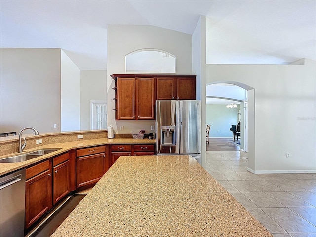 kitchen with tile patterned floors, stainless steel appliances, sink, vaulted ceiling, and light stone counters