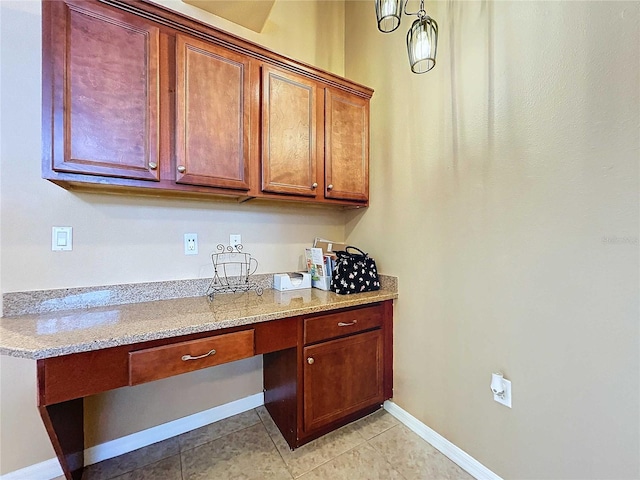 kitchen featuring built in desk, light stone counters, and light tile patterned floors