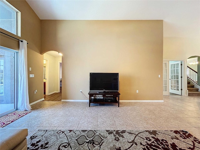 unfurnished living room with light tile patterned flooring and a high ceiling