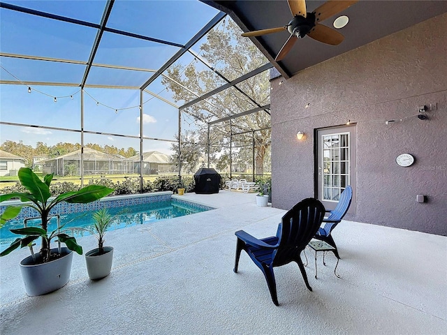 view of pool with a patio area, glass enclosure, and ceiling fan