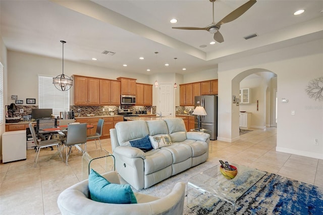 tiled living room featuring sink and ceiling fan with notable chandelier