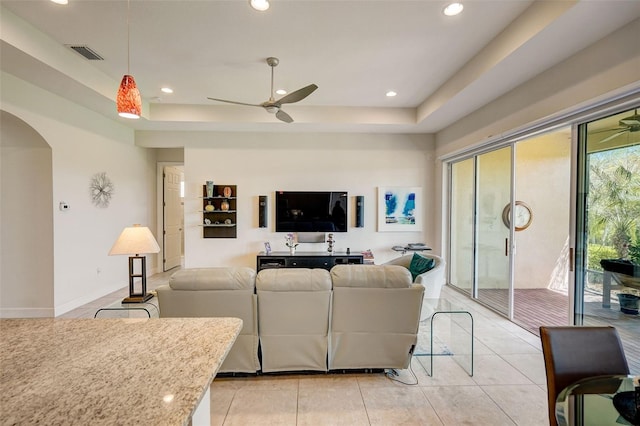 living room with ceiling fan, light tile patterned floors, and a raised ceiling