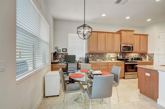 kitchen with stainless steel appliances, a notable chandelier, decorative light fixtures, light tile patterned floors, and light stone counters