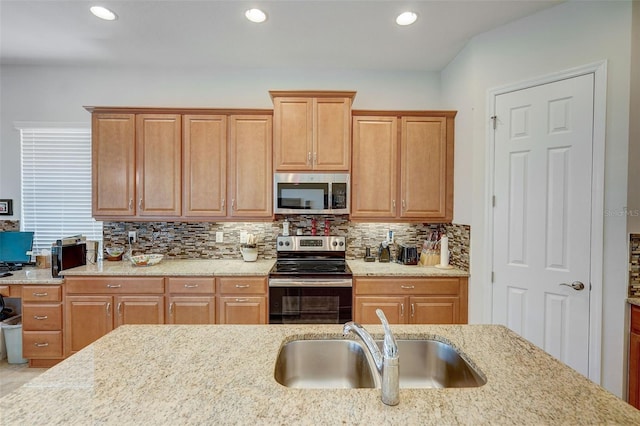 kitchen featuring appliances with stainless steel finishes, decorative backsplash, sink, and light stone counters