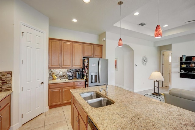 kitchen with decorative backsplash, light stone countertops, stainless steel appliances, sink, and decorative light fixtures