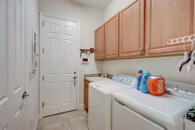 laundry area featuring sink, washer and clothes dryer, light tile patterned floors, and cabinets