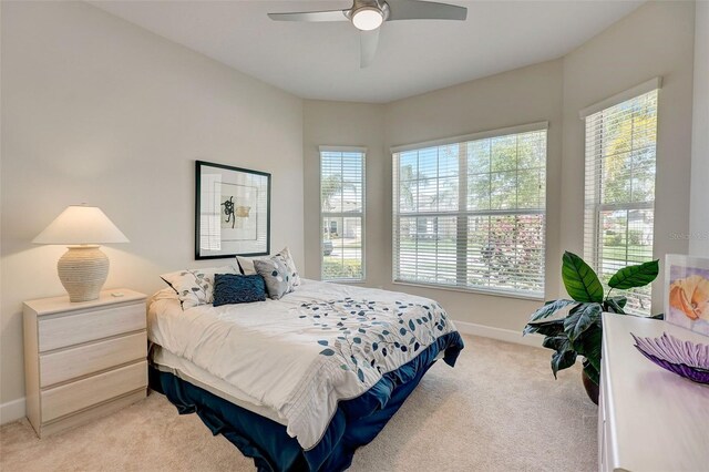 bedroom with ceiling fan, multiple windows, and light colored carpet