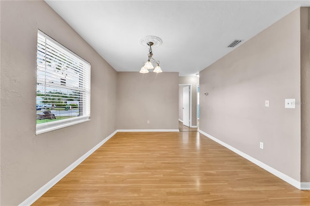 spare room with light hardwood / wood-style flooring and a chandelier