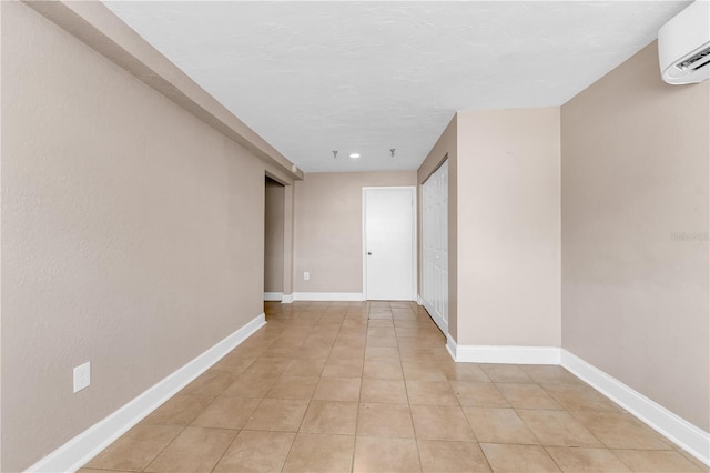 hallway with a textured ceiling, a wall mounted AC, and light tile patterned floors