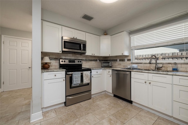 kitchen featuring white cabinetry, stainless steel appliances, sink, and backsplash