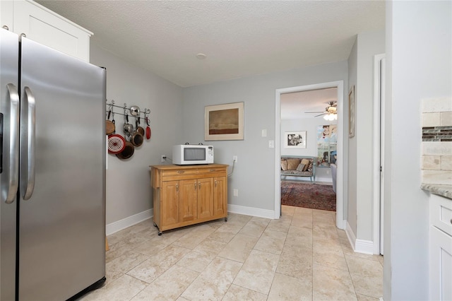 kitchen with white cabinets, stainless steel refrigerator, a textured ceiling, and ceiling fan