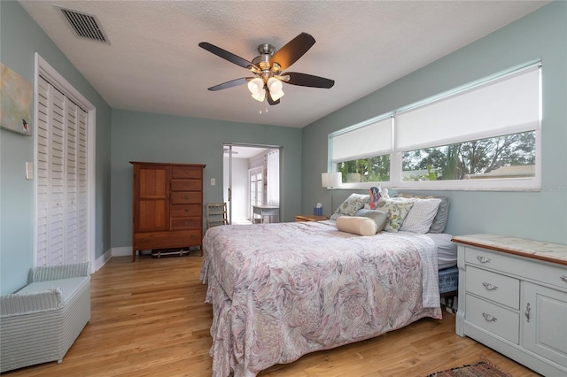 bedroom with a textured ceiling, light hardwood / wood-style flooring, and ceiling fan