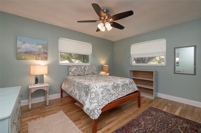 bedroom featuring light hardwood / wood-style floors, multiple windows, and ceiling fan