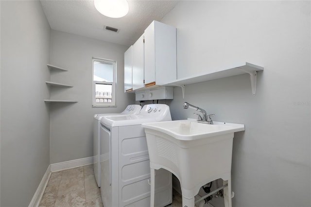 washroom with a textured ceiling, washing machine and dryer, and cabinets