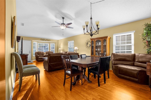 dining space with visible vents, ceiling fan with notable chandelier, and wood finished floors