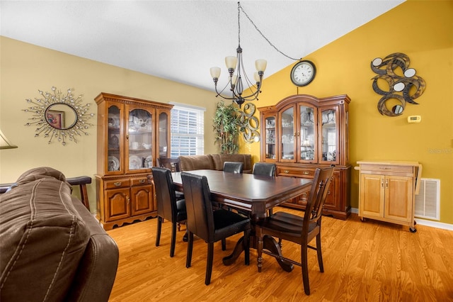 dining room featuring visible vents, lofted ceiling, light wood finished floors, and a chandelier