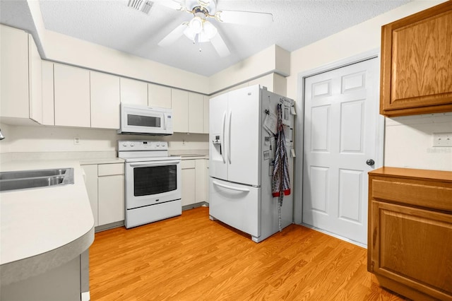 kitchen with a ceiling fan, visible vents, light wood-type flooring, a sink, and white appliances