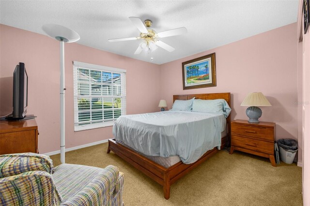 bedroom featuring light carpet, a textured ceiling, and ceiling fan