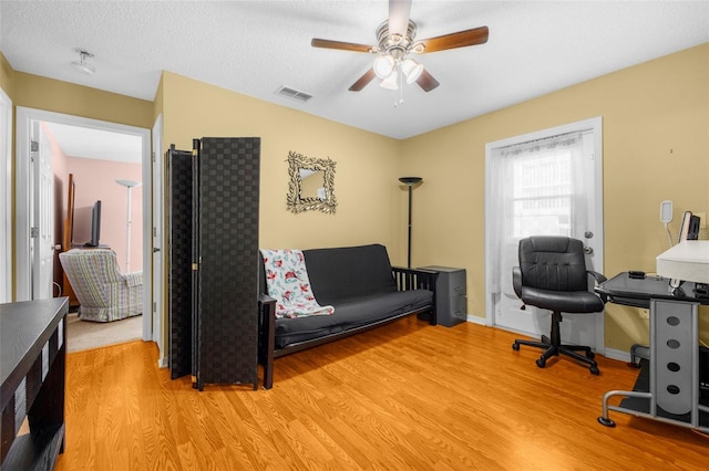 home office with baseboards, ceiling fan, light wood-type flooring, and visible vents