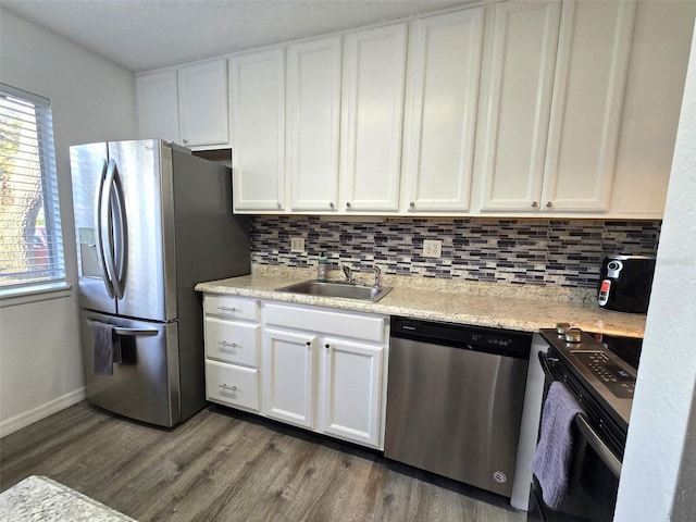 kitchen with tasteful backsplash, appliances with stainless steel finishes, white cabinetry, dark wood-type flooring, and sink