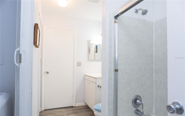 bathroom featuring vanity, a shower with shower door, toilet, and wood-type flooring