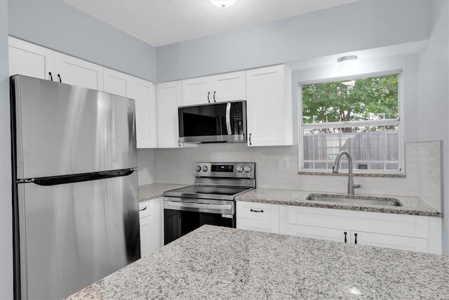 kitchen with tasteful backsplash, sink, white cabinetry, stainless steel appliances, and light stone counters