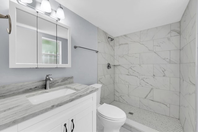 bathroom with vanity, a tile shower, and toilet