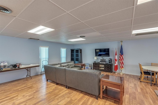 living room with a drop ceiling and wood-type flooring