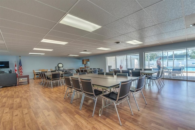 dining space with wood-type flooring and a paneled ceiling