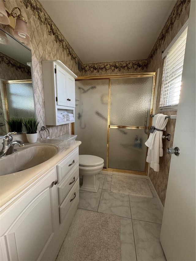 bathroom with a shower with door, vanity, toilet, and tile patterned floors