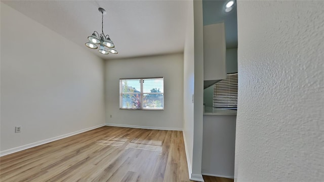 unfurnished dining area with light hardwood / wood-style floors and an inviting chandelier