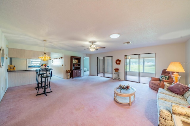 carpeted living room with ceiling fan and a textured ceiling