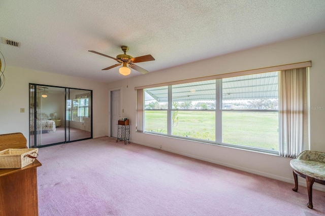 unfurnished room featuring a textured ceiling, light colored carpet, and ceiling fan