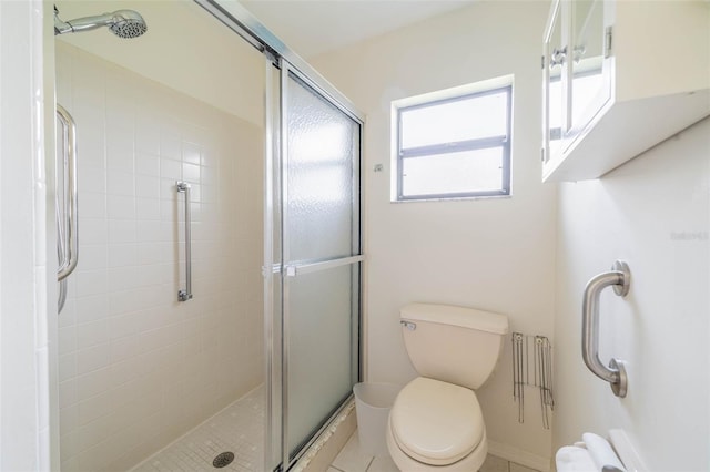 bathroom with a shower with door, toilet, and tile patterned floors