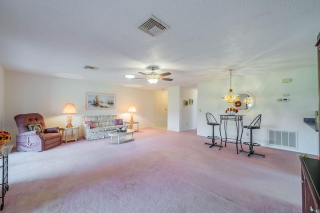 living room featuring a textured ceiling, light colored carpet, and ceiling fan with notable chandelier