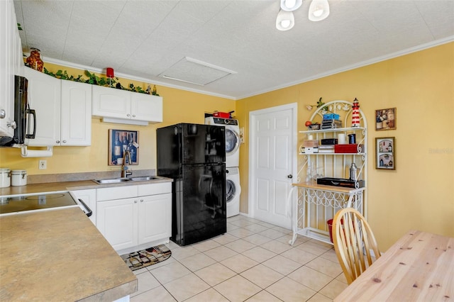 kitchen featuring white cabinetry, sink, stacked washing maching and dryer, black appliances, and ornamental molding