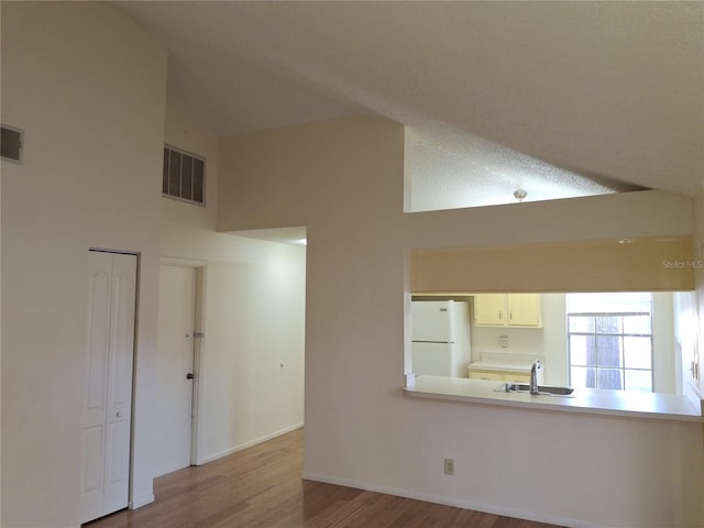 kitchen featuring sink, high vaulted ceiling, light wood-type flooring, and white refrigerator